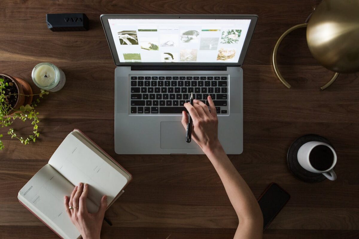 An overhead shot of a desk setup featuring a laptop, notebook, pen, and coffee cup, ideal for work and productivity themes.